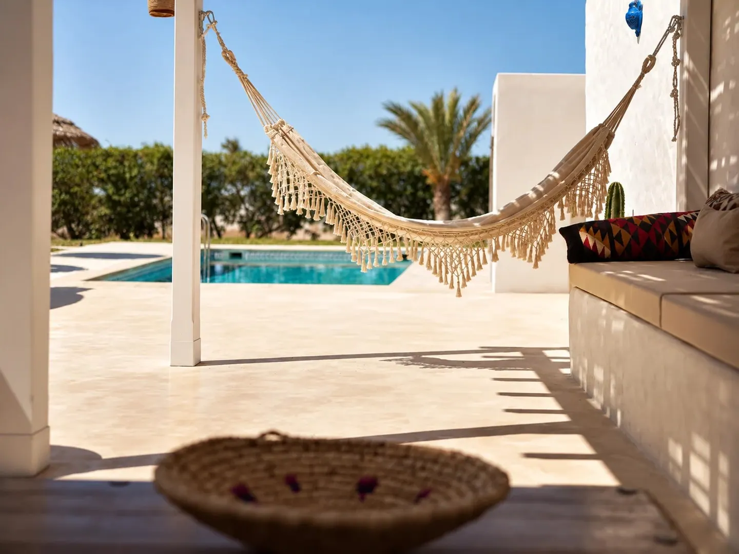 Hamac à franges sous la pergola, face à la piscine